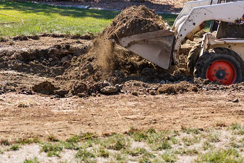 Loader dumping dirt on landscape site